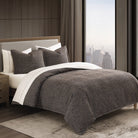 Bedroom with a bed featuring a brown tweed comforter and pillows, next to a window with a cityscape view.