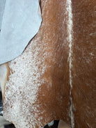 Image of brown and white peppered cowhide rug hung up