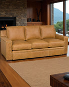 Brown leather sofa in a living room with a fireplace and large windows - Your Western Decor