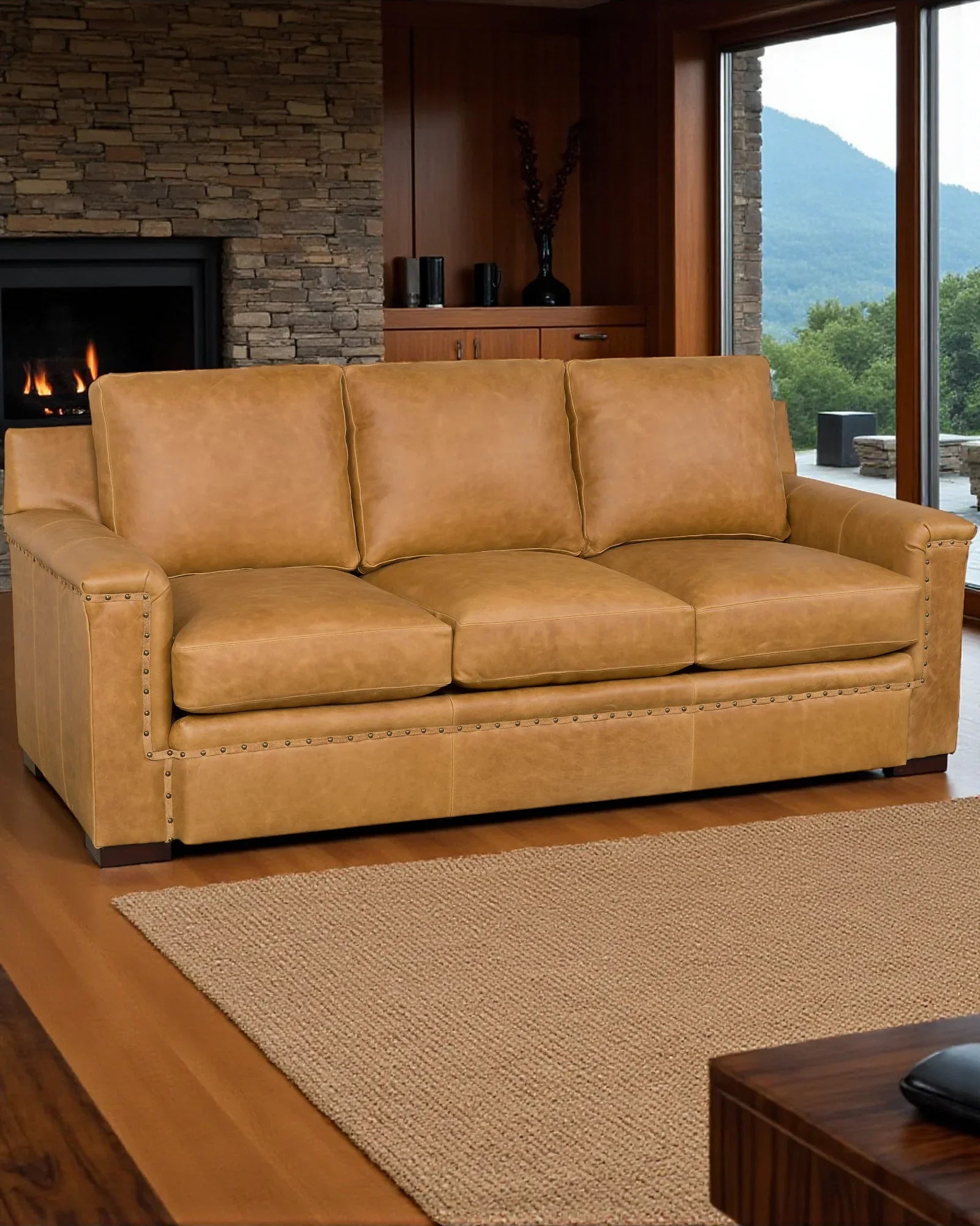 Brown leather sofa in a living room with a fireplace and large windows - Your Western Decor