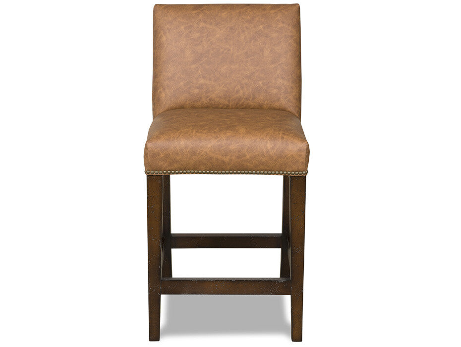 A single upholstered bar stool with a warm tan faux-leather seat and backrest, dark brown wooden legs, and nailhead trim along the front edge, shown against a plain white background.