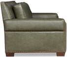 Sage green leather sofa side showing leather trim and nail tacking with wood legs