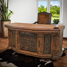 Western desk with wood carvings, tooled leather panels, marble top, and iron with clavos accents - featured cowhide office and chair and cowhide rug - Your Western Decor