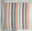 A roll of striped fabric laid flat on a white grid cutting mat. The fabric has vertical stripes in orange, gray, dark blue, and cream.