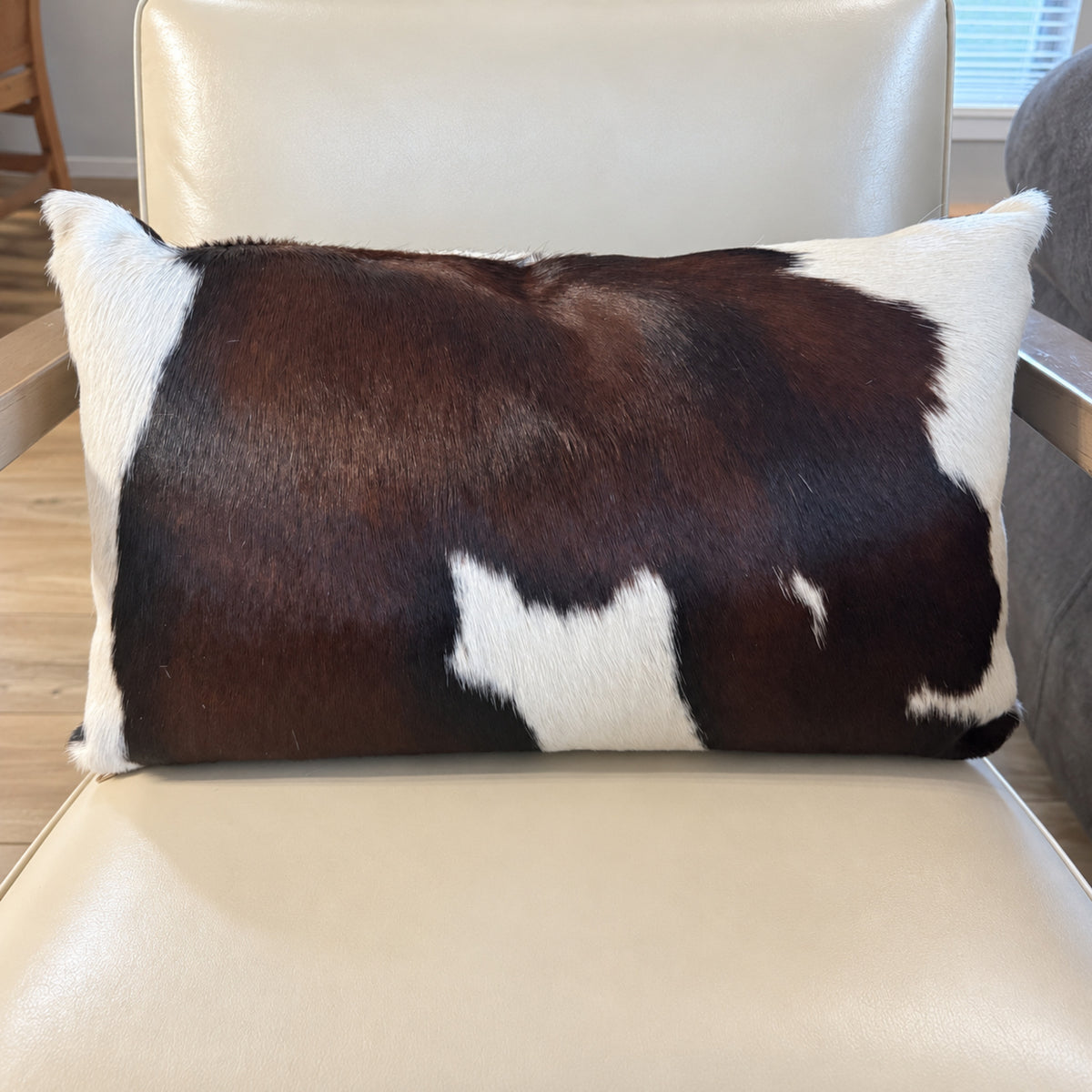 Chocolate and white cowhide lumbar pillow by Saddlemans on cream leather recliner 