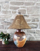 Decorative lamp with a brown lampshade against a stone wall - Your Western Decor