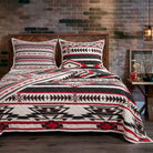 Coal Creek Aztec quilt set in black, ivory and crimson Southwestern geometric pattern styled on rustic Western bed with wood headboard