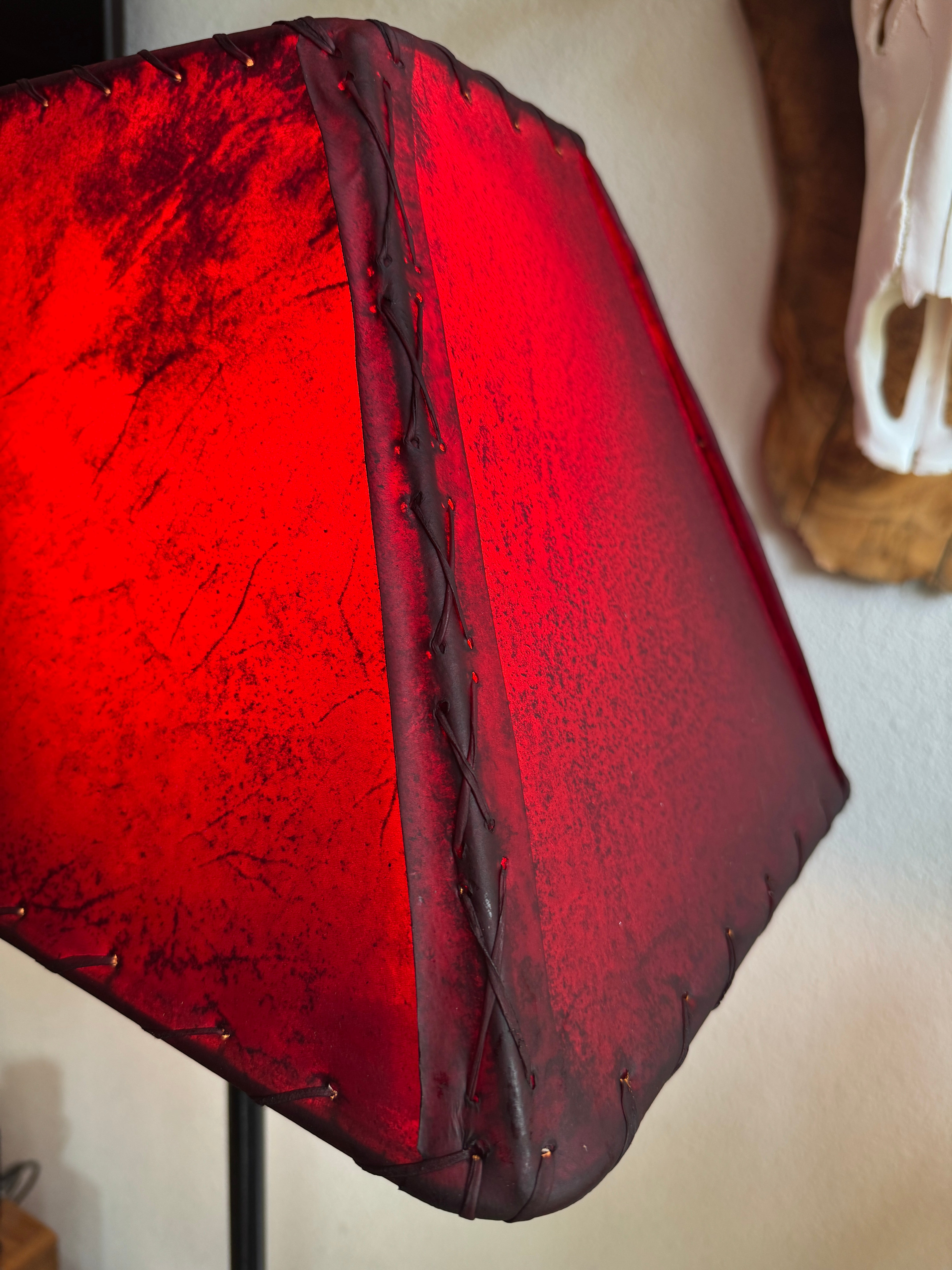 Whip stitching corner view of red rawhide lampshade with the light on