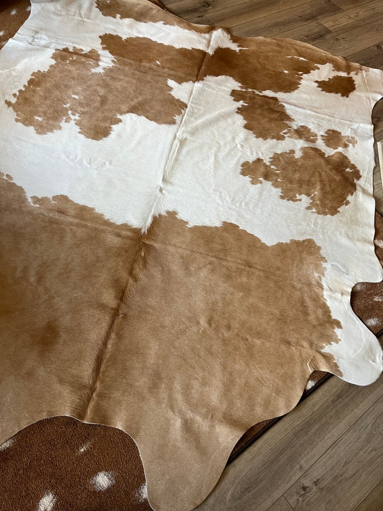 Brown and white cowhide rug on a wooden floor