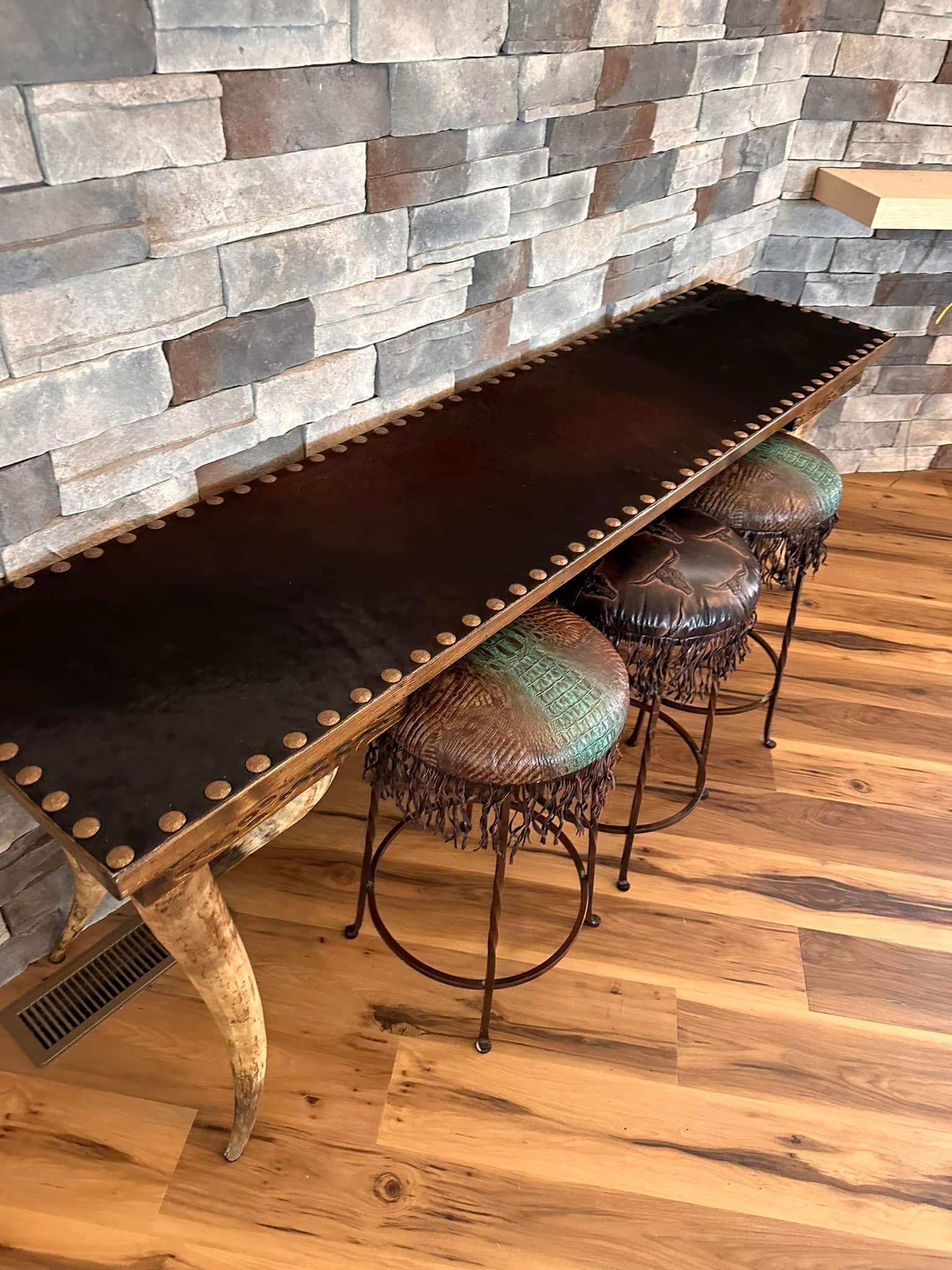 Custom made longhorn leg and cowhide sofa table and leather and iron counter stools 