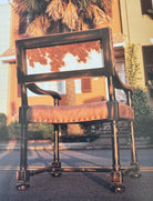 Brown white cowhide back and smooth leather exposed wood accent chair outdoors 