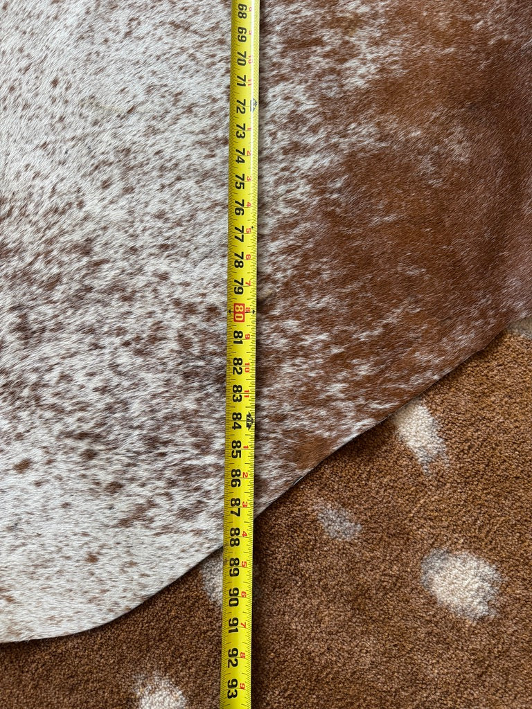 Measurement tape on a brown and white cowhide rug