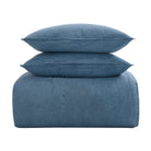 A three-piece bedding set in a dusty blue denim-like fabric, featuring a folded sheet or duvet cover with a stitched seam, two matching square pillows, and one larger rectangular pillow, stacked neatly on a solid white background.