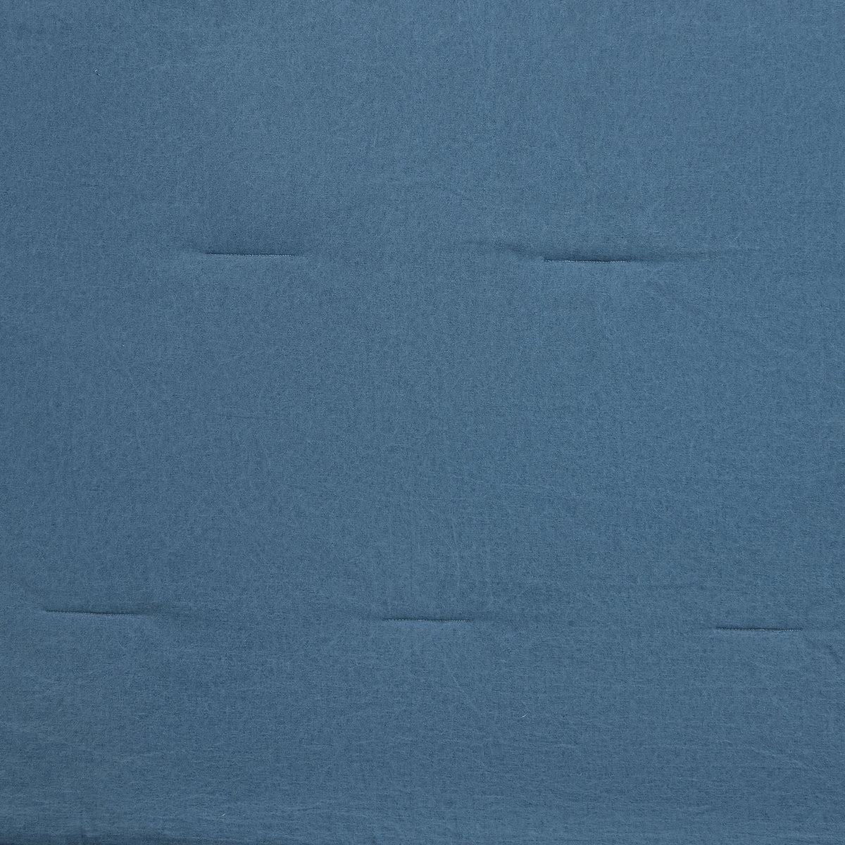 A close-up of a textured blue fabric surface with subtle horizontal stitched seams.