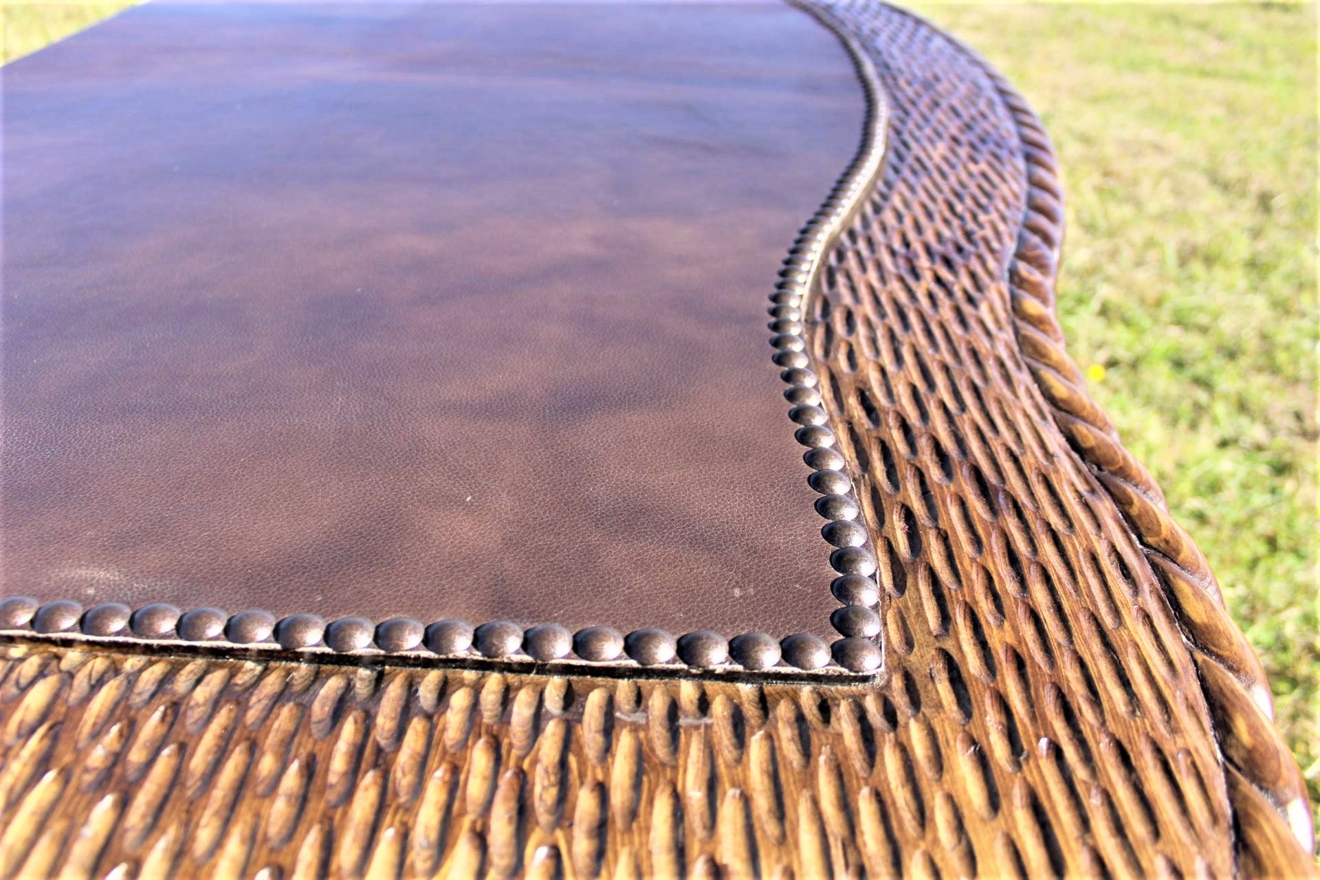 Detailed image of carved and chiseled desk top with leather surface and nail trim 