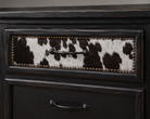 Detail of dresser drawer front with black and white cowhide upholstery and nailhead trim 