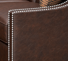 Close-up of silver nailhead trim on dark brown leather sofa arm