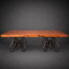 A rustic rectangular table with a distressed copper top and ornate dark metal scrollwork legs, photographed against a dark gray studio background.