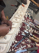 Woodworking scene with a person working on a piece of wood, surrounded by various tools on a red surface - Your Western Decor