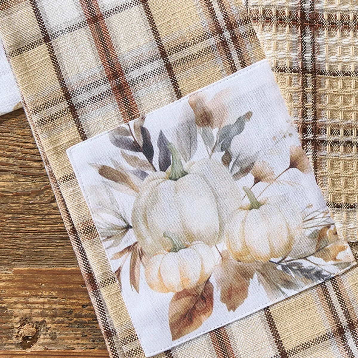 Decorative napkin with pumpkin design on a plaid dish towel - Your Western Decor