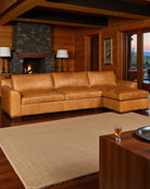 Brown leather sectional sofa in a cozy living room with wooden walls and a fireplace - Your Western Decor