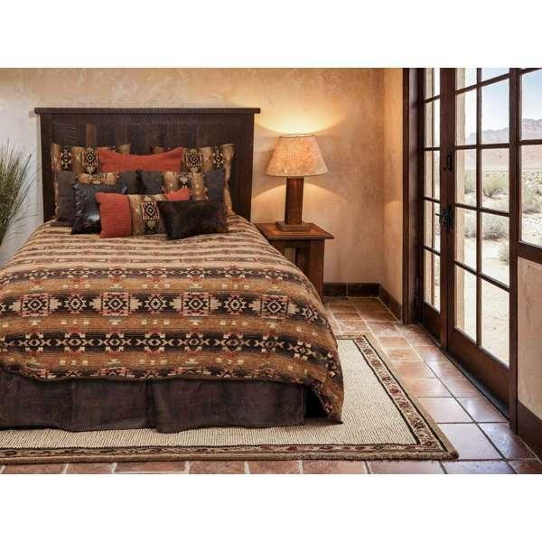 Bedroom with a bed featuring a patterned comforter and pillows, next to a lamp and open French door - Your Western Decor