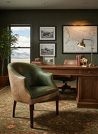 Cozy office with a green chair, wooden desk, and framed pictures on a dark wall - Your Western Decor