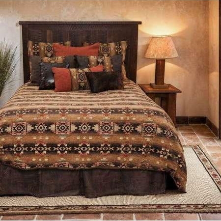 Bedroom with a bed featuring a patterned comforter and pillows, next to a lamp and a door leading outside.