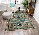 A rectangular area rug with a Southwestern geometric pattern in teal, beige, brown, and black, styled on a dark wood floor in a bright living room setting.