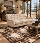 Ivory tufted leather sofa with Charles of London arms and nailhead trim in a Western ranch style living room setting