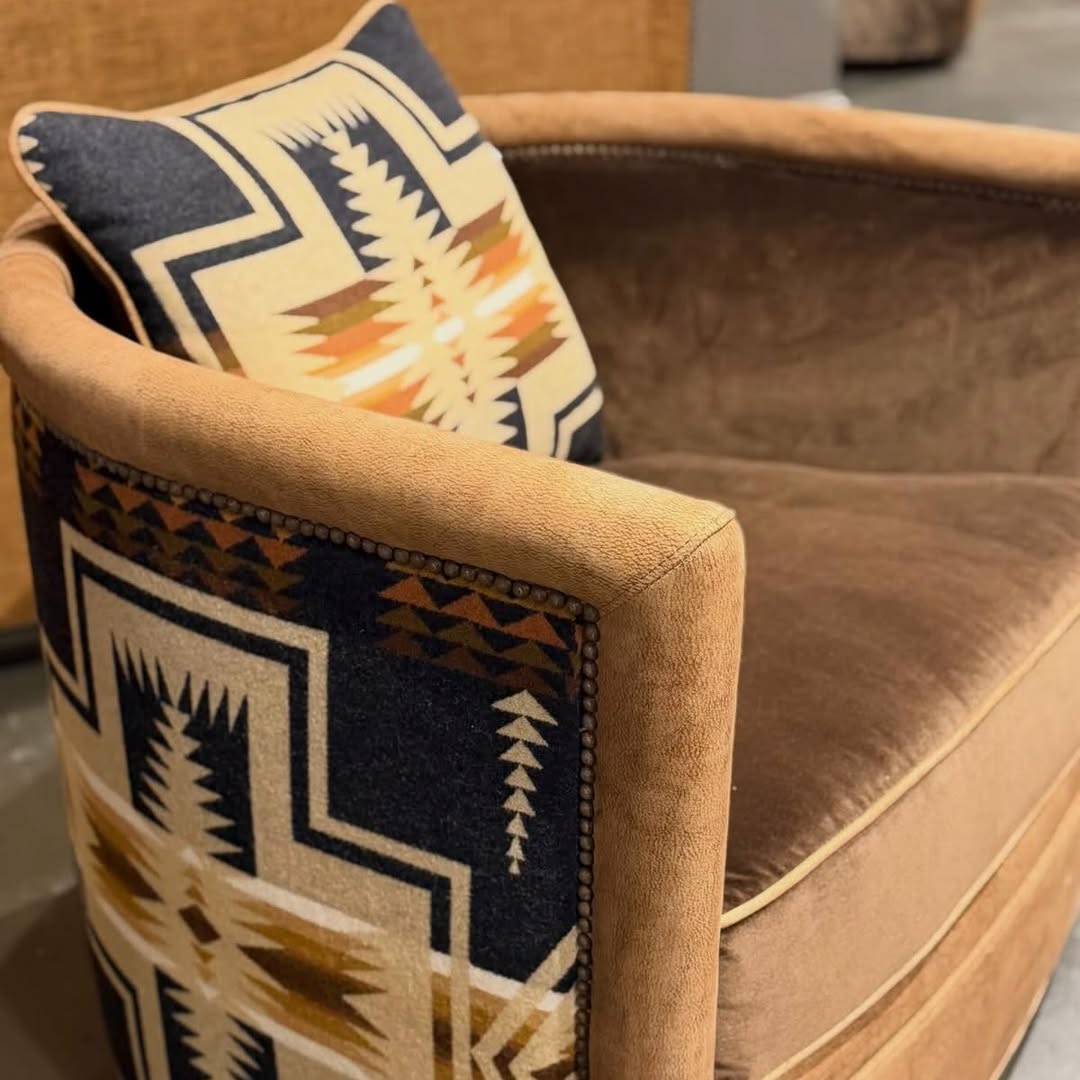 A close-up of a tan upholstered armchair with a matching accent pillow featuring a Southwestern Pendleton Harding geometric pattern in navy, cream, and tan.