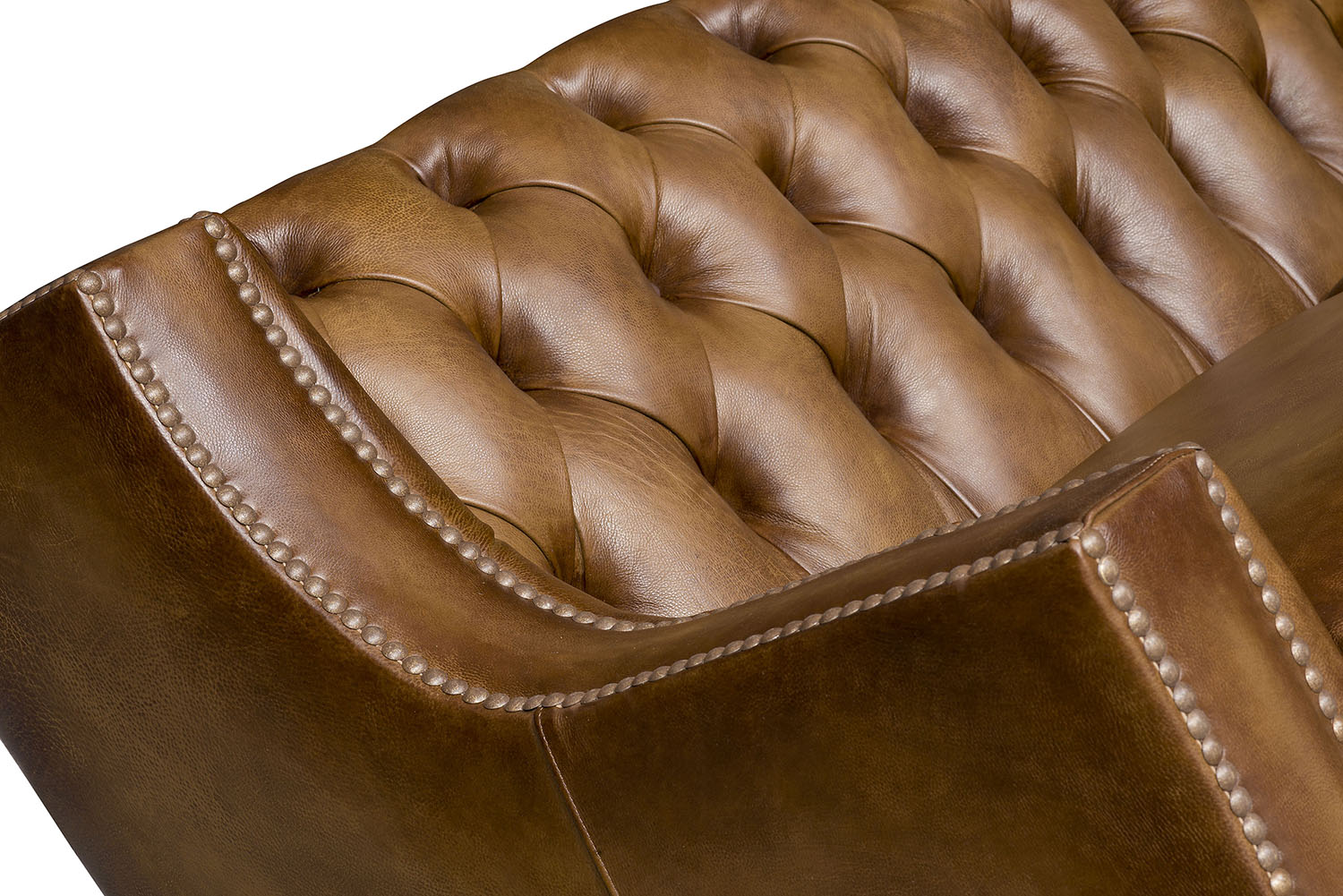 Close-up of a brown leather tufted sofa with visible stitching and nail trim 