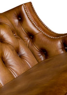 Close-up of a brown leather sofa with tufted backrest and button details 