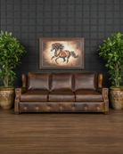 Brown leather sofa in a room with a dark wall, framed horse painting, and two potted plants 