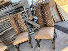 Two wooden chairs with deer-patterned backs in front of a pile of wooden planks - Your Western Decor