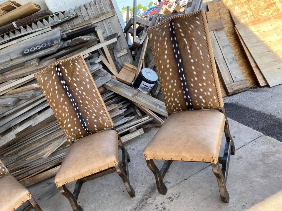 Two wooden chairs with deer-patterned backs in front of a pile of wooden planks - Your Western Decor