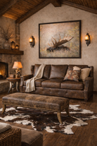 Cozy living room with rustic decor, including a brown sofa, ottoman, and Moose wall art - Your Western Decor