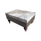 Decorative ottoman with brindle cowhide patterned top and wooden legs on a white background