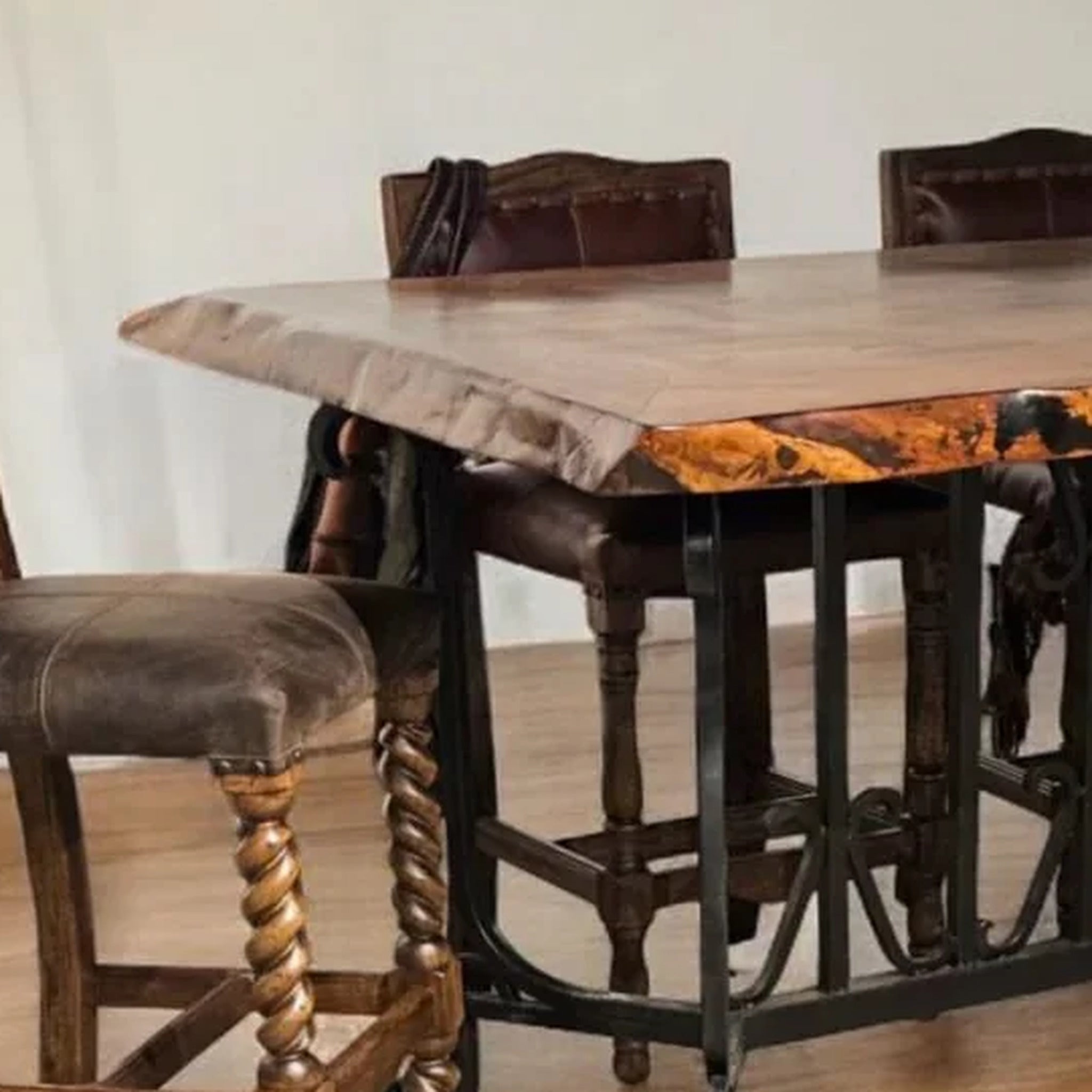 A rustic wooden bar height dining table with a live edge, paired with dark brown chairs featuring twisted wooden legs and dark upholstery, set in a dining room.