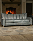Gray leather sofa in a living room with a fireplace and patterned rug - Your Western Decor