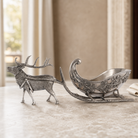 Decorative silver reindeer and sleigh on a wooden surface with a blurred indoor background