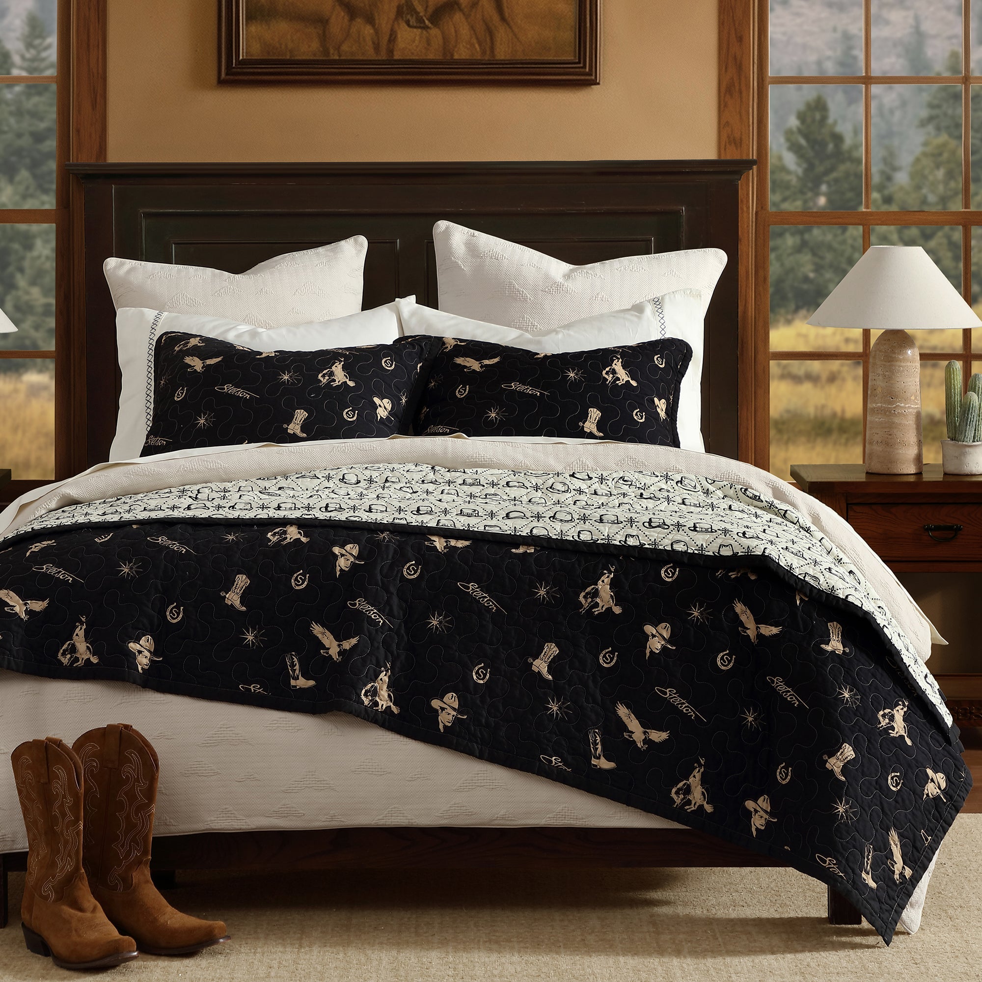 Bedroom with a bed featuring a black and white western patterned quilt, white pillows, and brown boots on the floor.