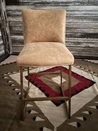 Beige leather bar stool against a rustic wooden wall with a patterned rug - Your Western Decor