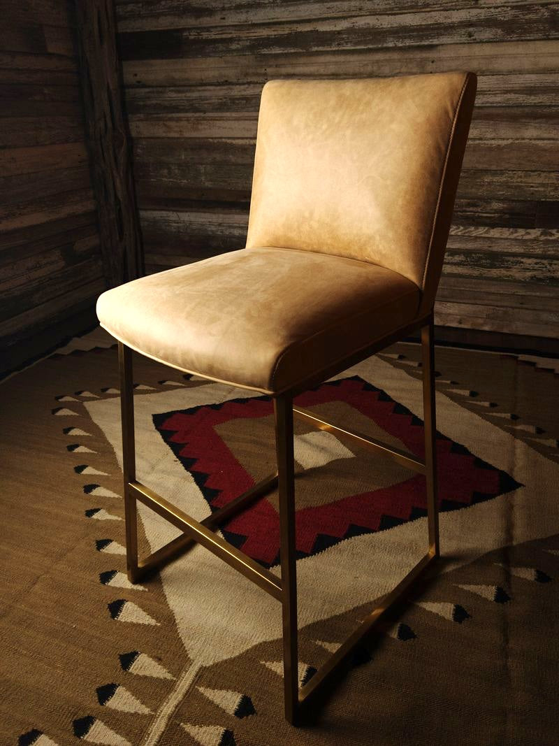 Beige leather chair on a patterned rug with wooden wall background - Your Western Decor