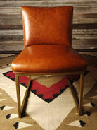 Brown leather dining chair on a patterned rug with a wooden wall background - Your Western Decor
