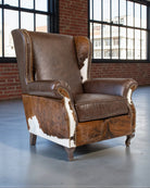 Brown leather armchair with cowhide pattern in a room with large windows and brick walls. Your Western Decor