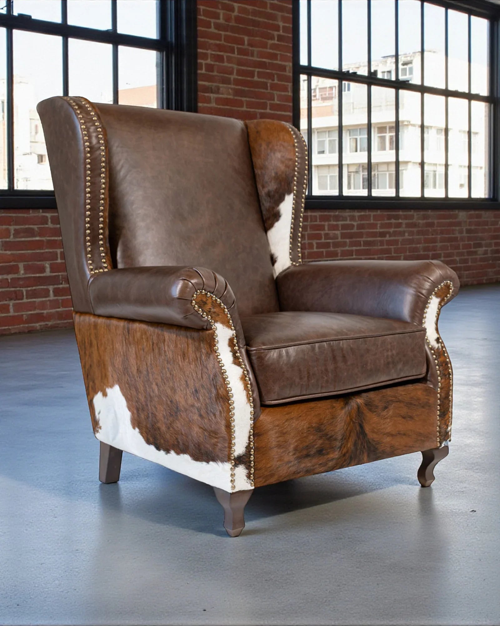 Brown leather armchair with cowhide pattern in a room with large windows and brick walls. Your Western Decor