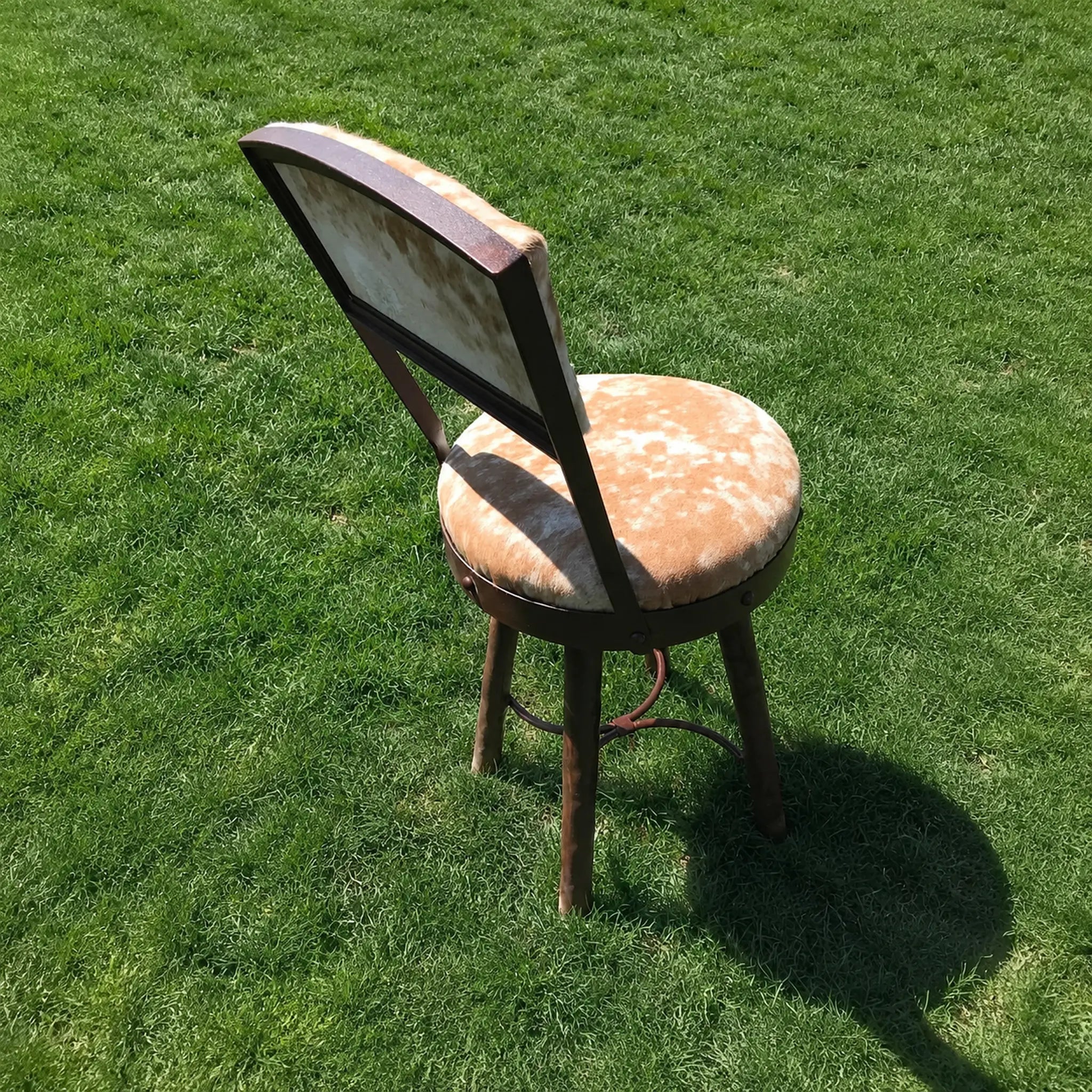 American made Peak 9 rustic western swivel counter stool upholstered in beige and white cowhide with an hand-forged iron frame