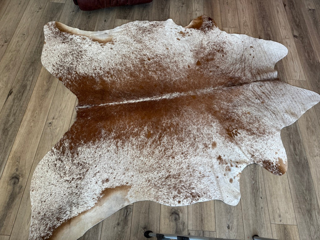 Brown and white peppered cowhide rug with brand