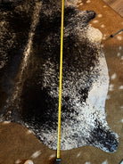 Measurement of a cowhide rug with a tape measure on a brown surface - Your Western Decor